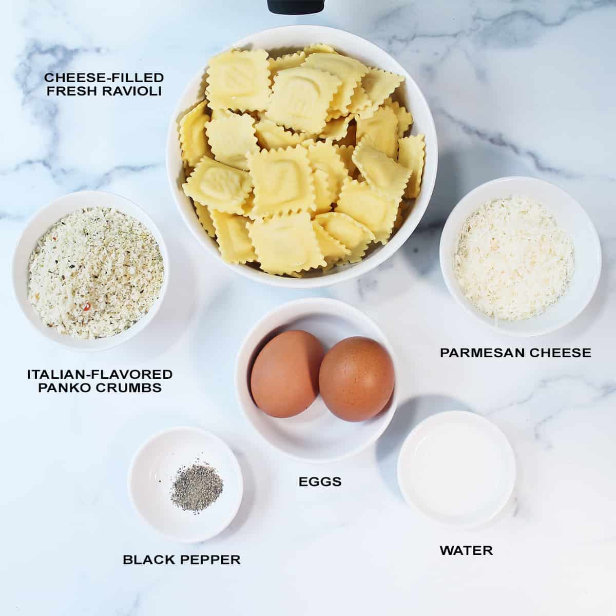 Air Fryer ravioli ingredients, labeled, on marble table.