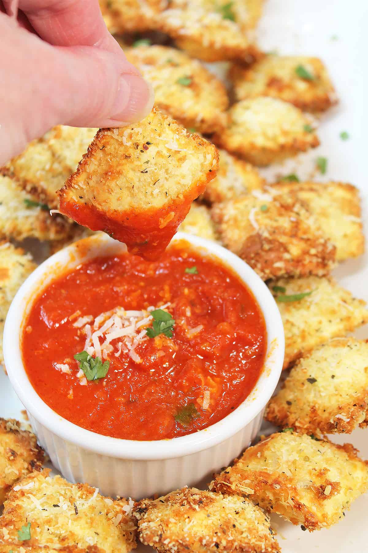 Dipped fried ravioli over platter of ravioli.