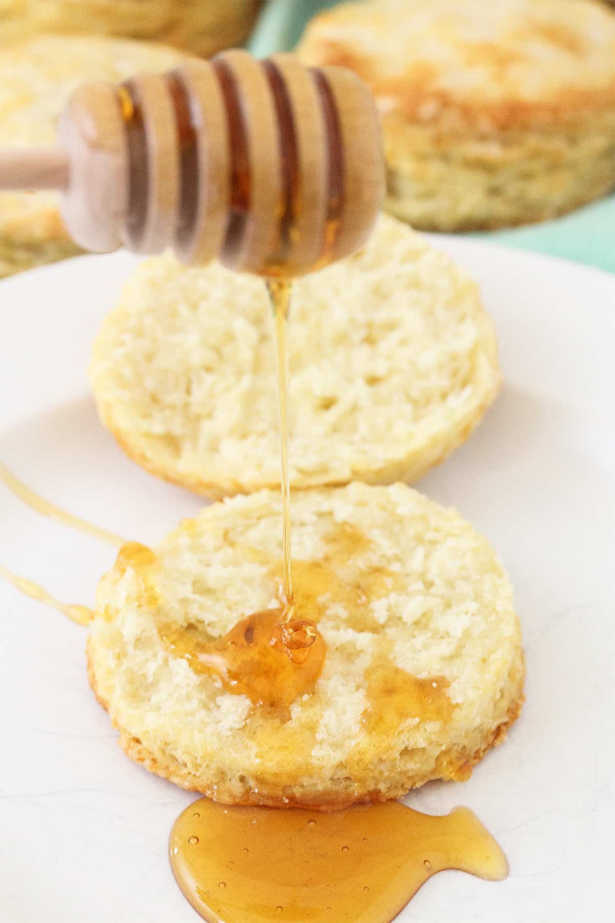 Drizzling honey on halved biscuit.