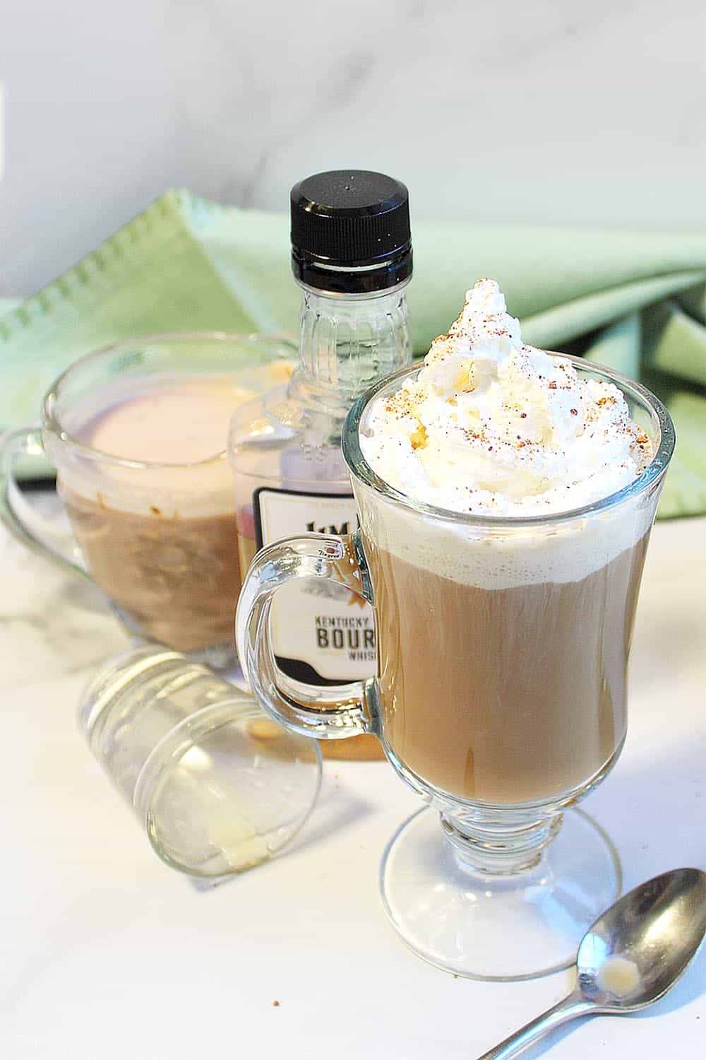 Irish Coffee topped with whipped cream beside whiskey bottle