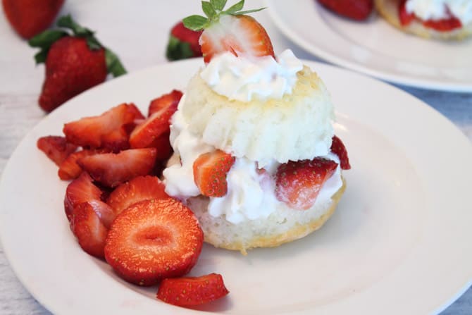 Closeup of shortcake filled with whipped cream and strawberries and topped with half a strawberry.