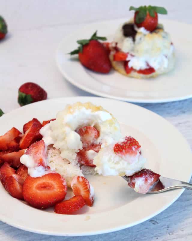 Taking a bite of the shortcake with untouched shortcake in background.