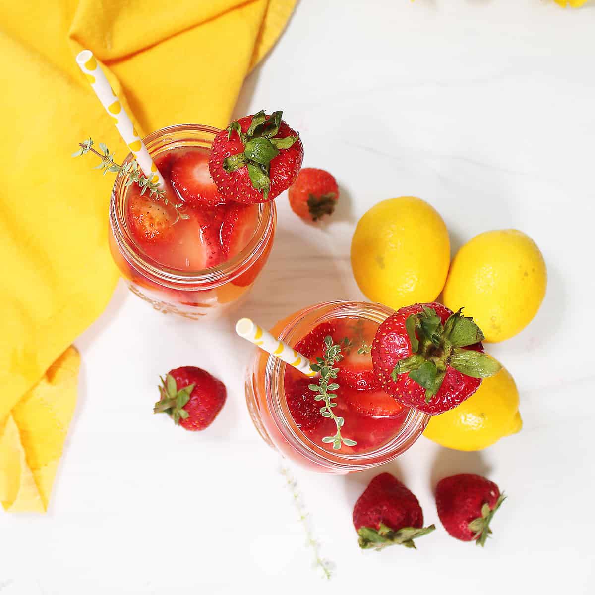 Overhead of strawberry lemonade next to lemons.