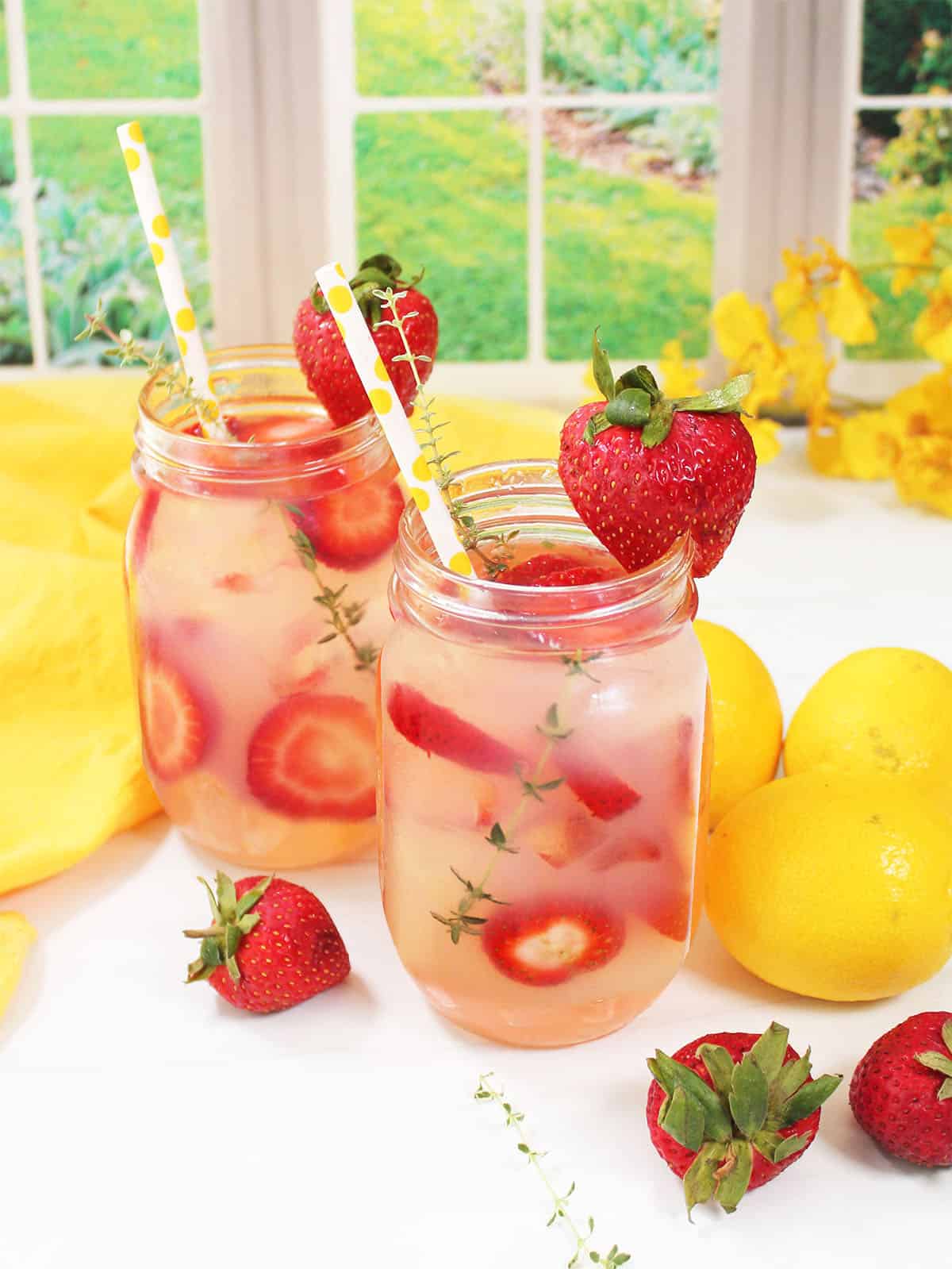 2 Strawberry Thyme Lemonades in mason jars garnished with strawberry.