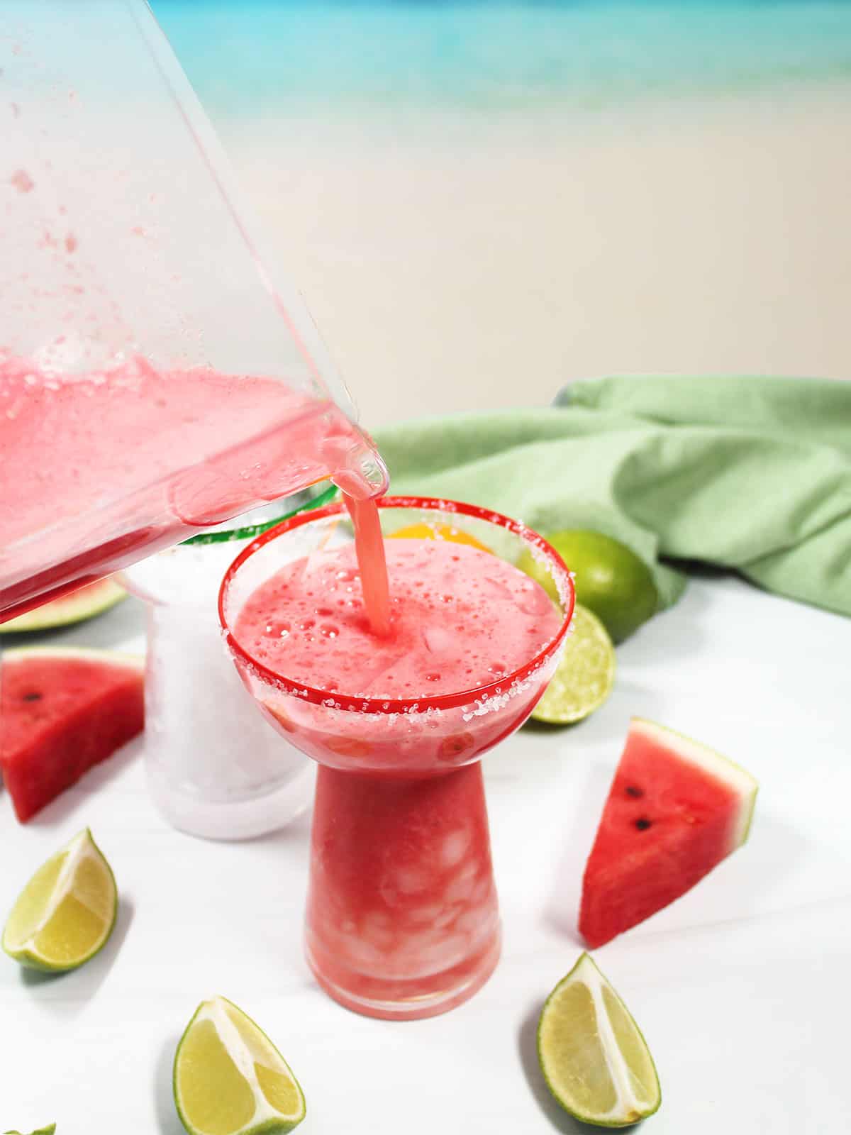 Pouring watermelon cocktail into salt rimmed glass.
