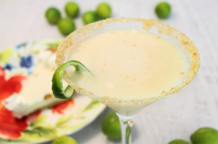 Martini closeup showing how creamy the drink is with a piece of key lime pie behind it.