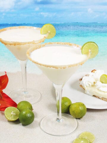 Two key lime pie martinis with lime wheel and graham cracker rim.