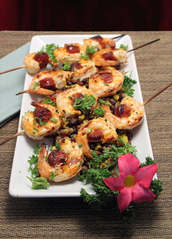 Shrimp & Chorizo Skewers closeup with red flower on white platter.