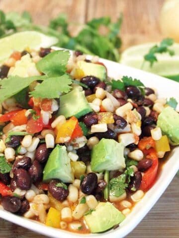 Closeup of salad in white bowl with avocado on top.