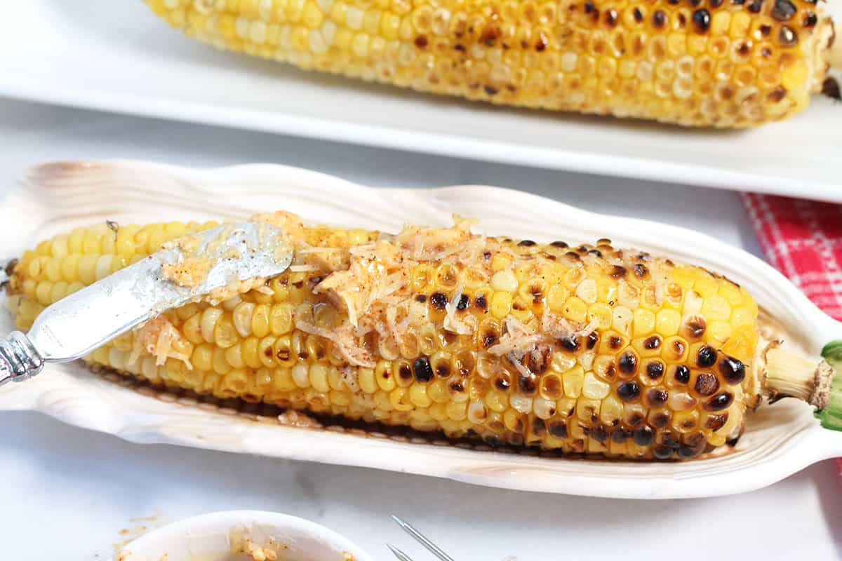 Closeup of sweet grilled corn on the cob with chili butter smeared on top.