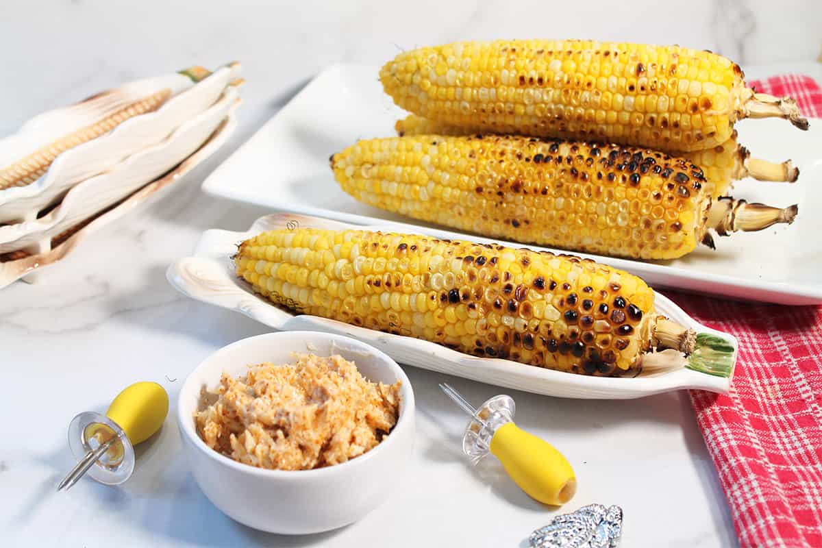 Grilled Mexican corn in corn dishes with parmesan chili butter in front.