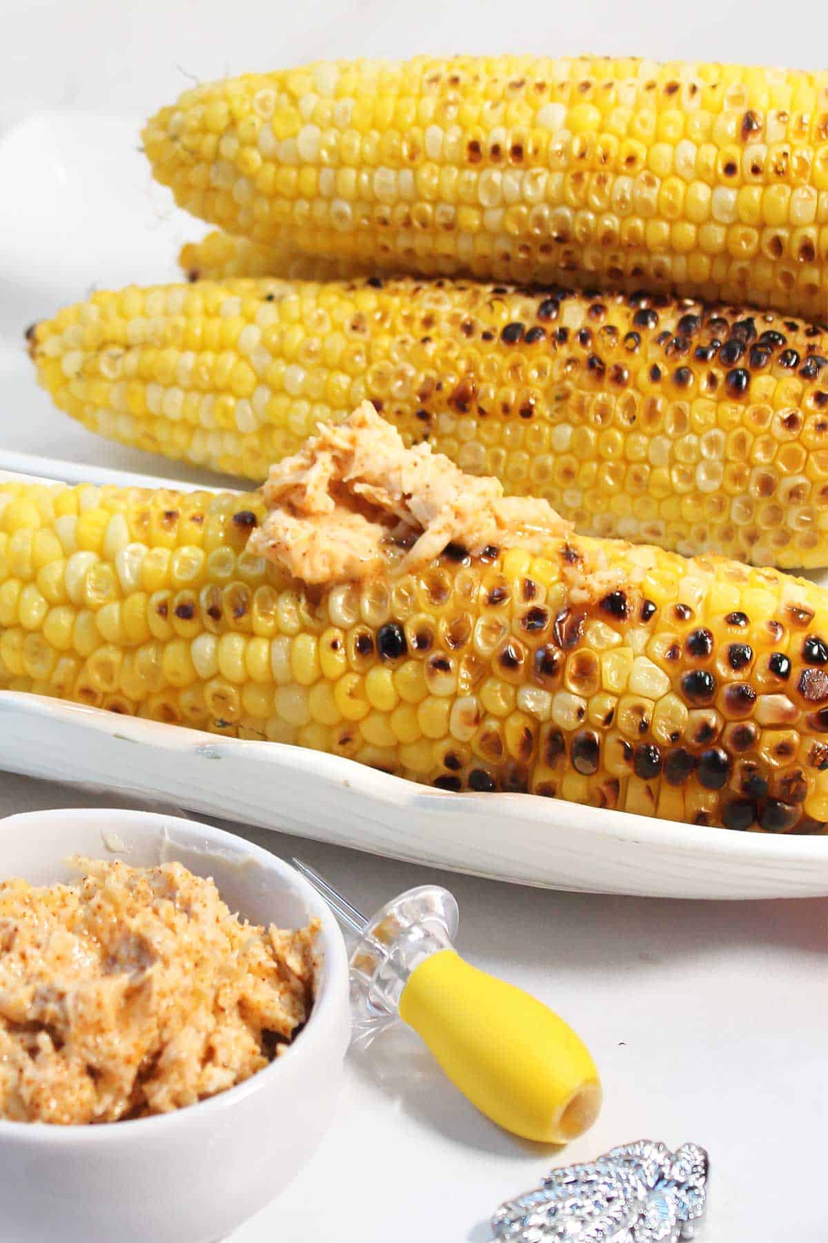 Grilled corn on cob with parmesan chili butter smeared on front ear.