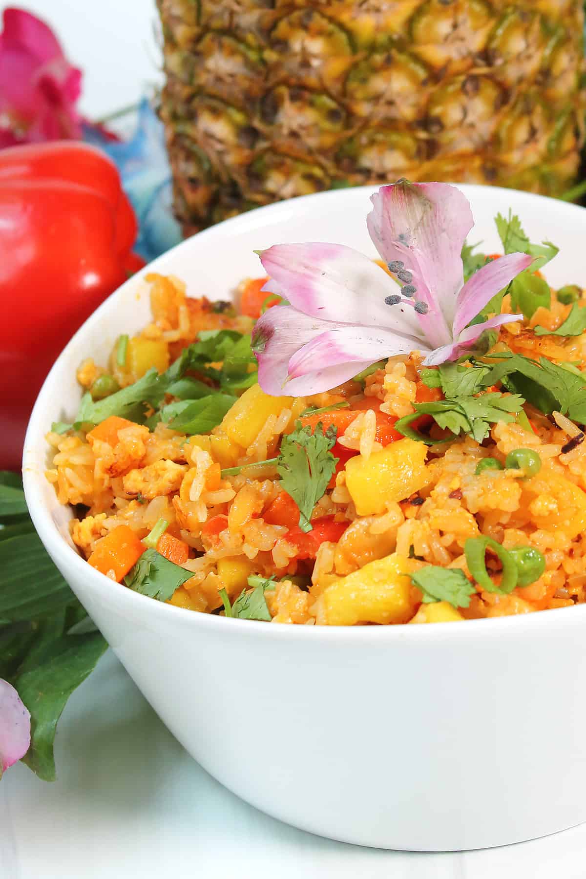 Partial bowl of Pineapple Fried Rice with flower on top.