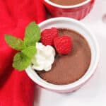 Chocolate filled ramekin with whipped cream and berries.