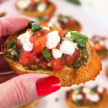 Holding bruschetta with pesto and mozzarella.