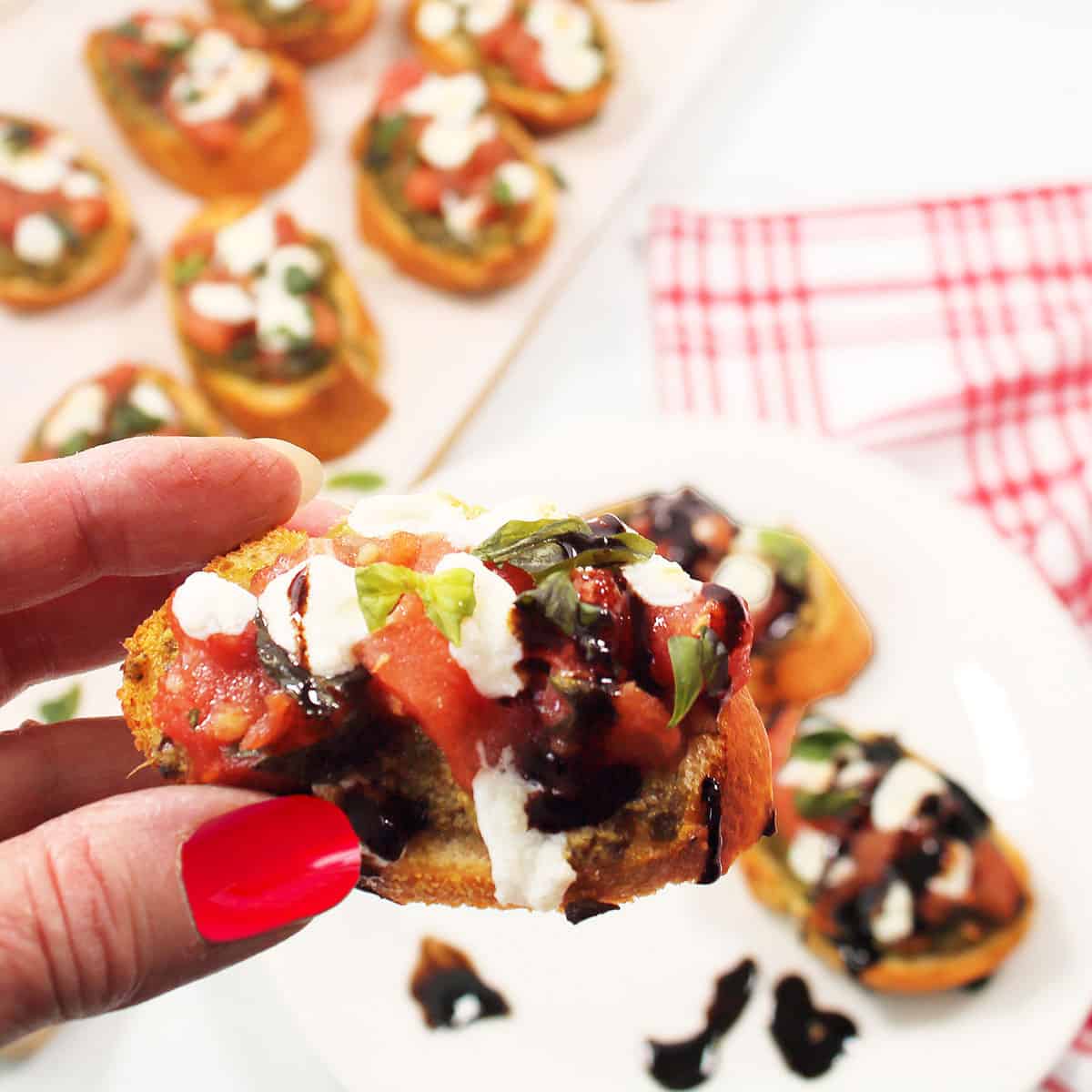 Holding pesto appetizer with balsamic drizzle.