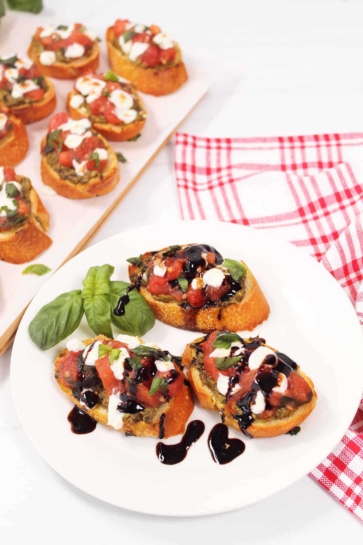 Three pesto bruschetta on plate with balsamic drizzle.