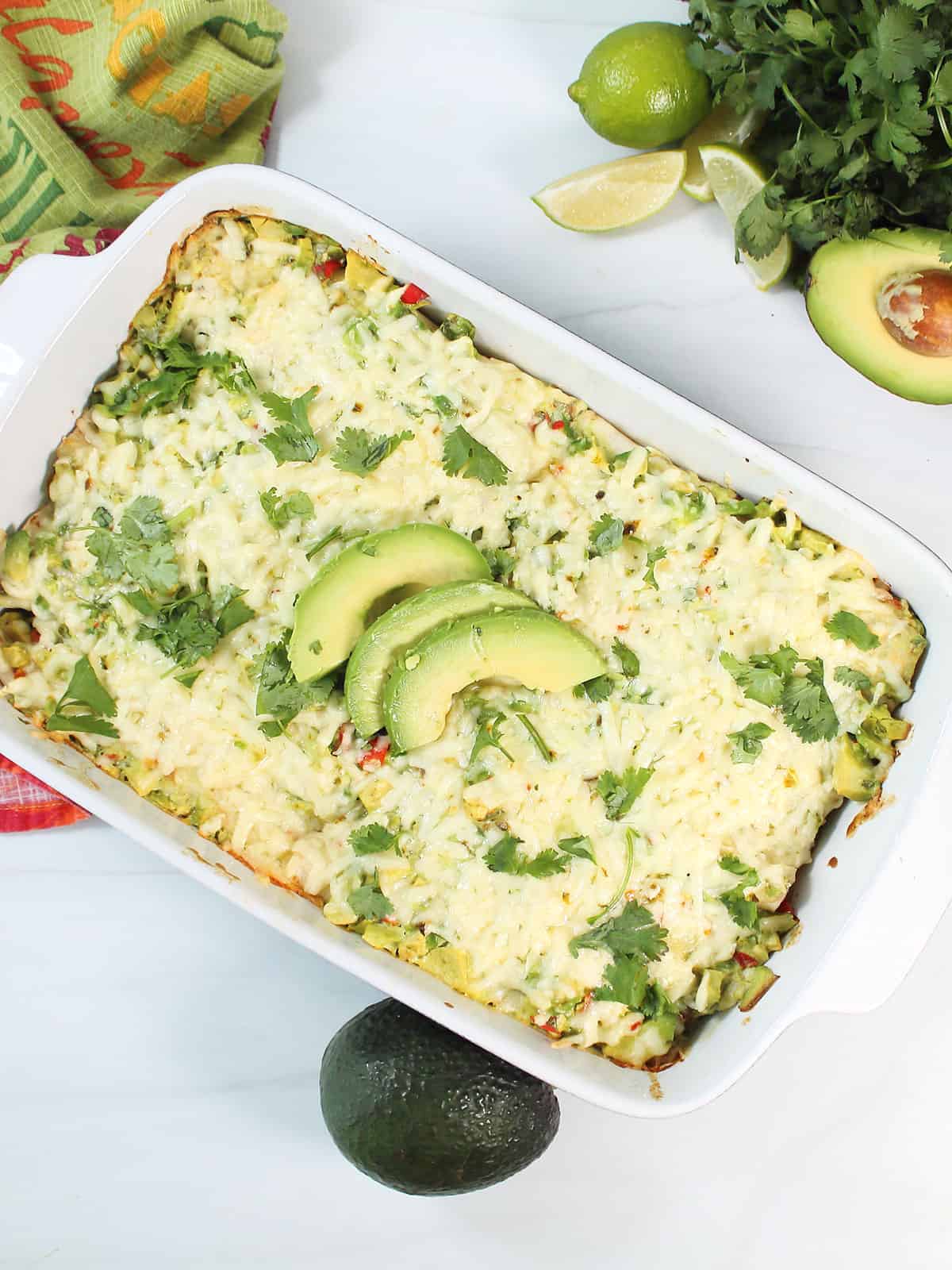 Baked enchilada casserole with avocado slices and cilantro garnish.