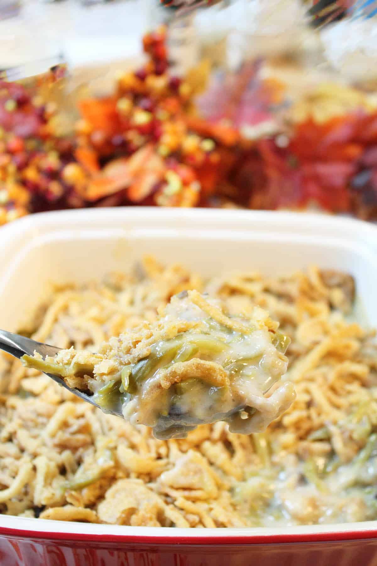 Closeup of spoonful of classic green bean casserole over full hot casserole.