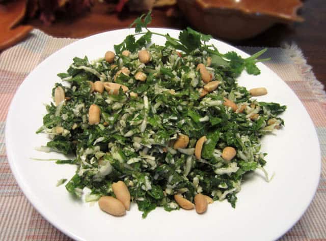 Kale Salad in white bowl with peanuts on top.