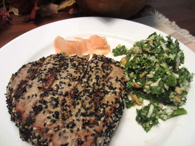 Kale Salad beside ahi tuna with ginger on white plate.