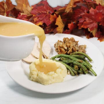 Pouring gravy over mashed potatoes.