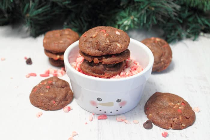Chocolate Peppermint Pudding Cookies in bowl with snowman face and other cookies scattered around.