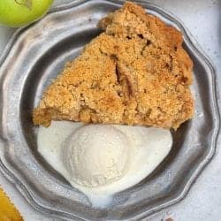 Overhead of slice of pie on pewter plate with scoop of vanilla ice cream.
