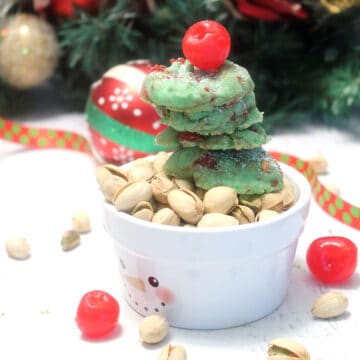 Stack of cookies sitting on pistachio nuts.