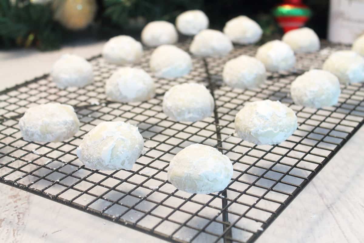 Powdered sugar coated snowball cookies on wire rack.