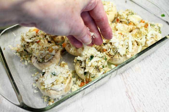 Filling mushrooms and sprinkling cheese on top.