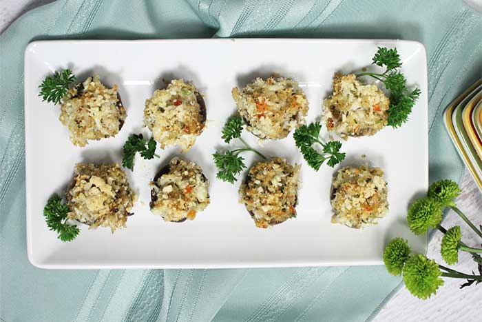Overhead of finished Crab Stuffed Mushrooms with parsley garnish on white platter.