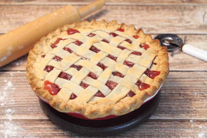 Baked Cherry Pie on wooden table with rolling pin.