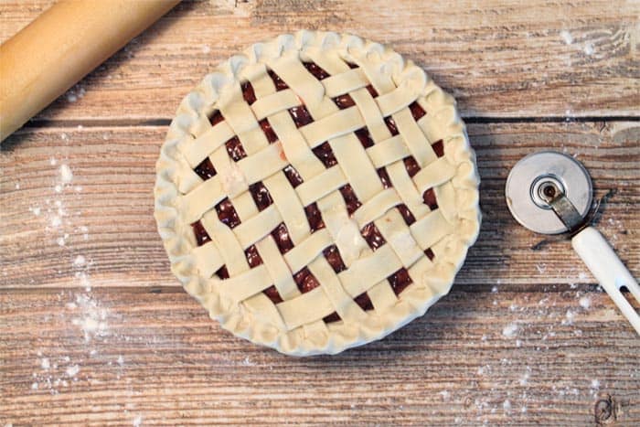 Cherry Pie with lattice crust on wooden table prior to baking.