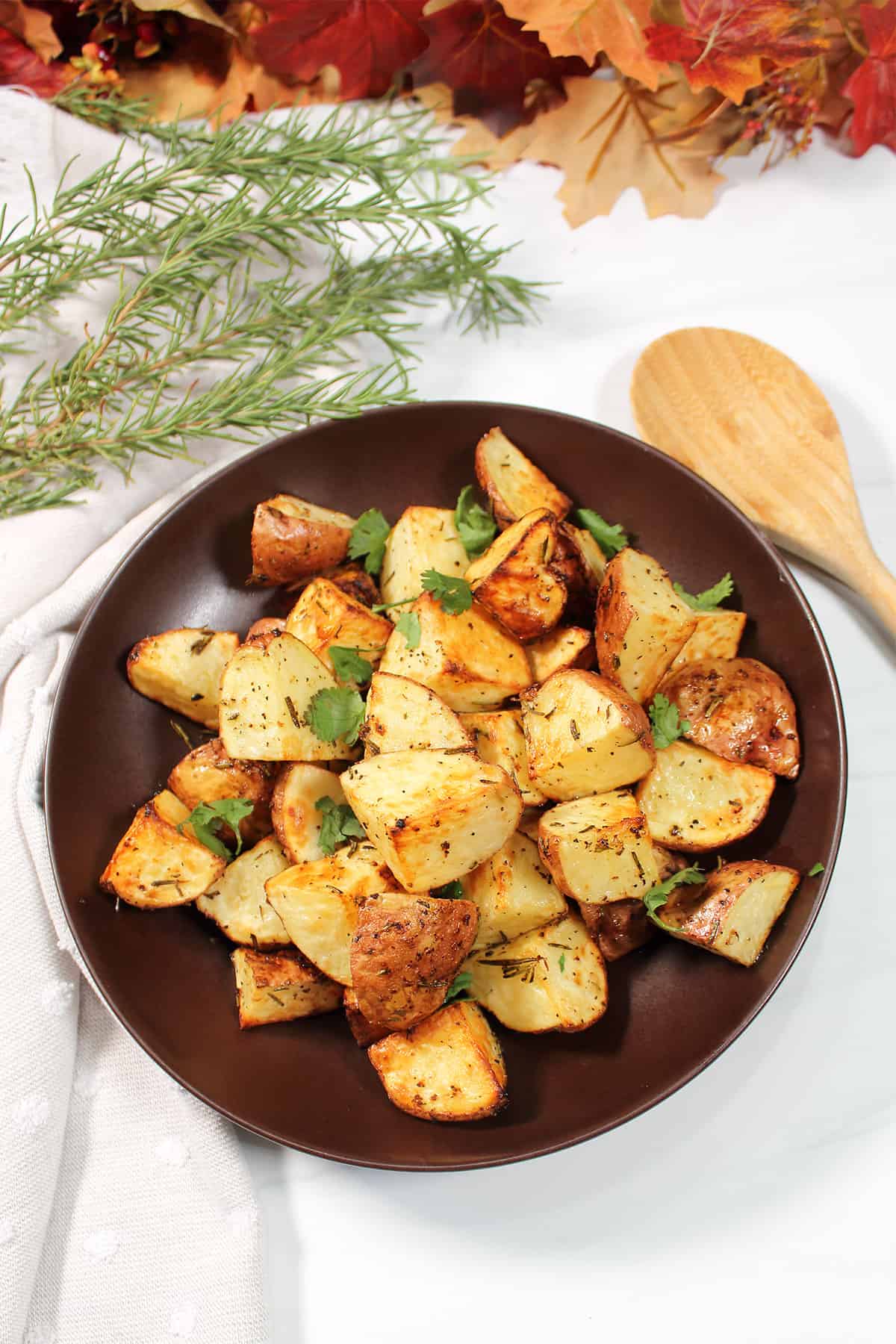 Overhead of air fryer rosemary potatoes with sprigs of rosemary.