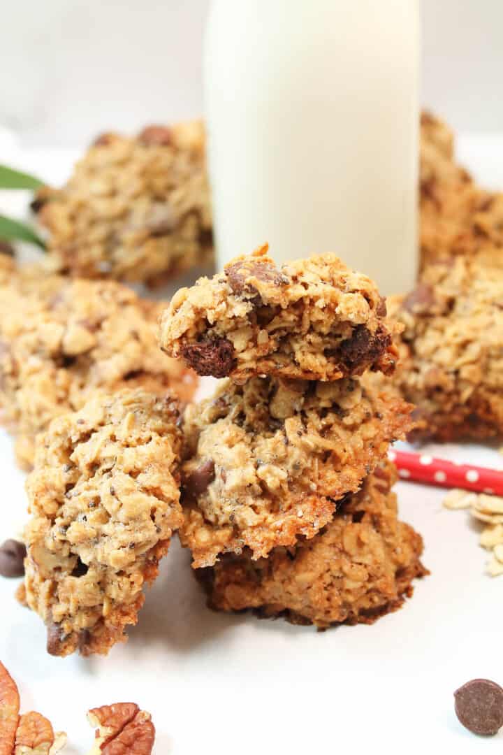 Closeup of stacked oatmeal cookies with bite out of one in front of milk bottle.