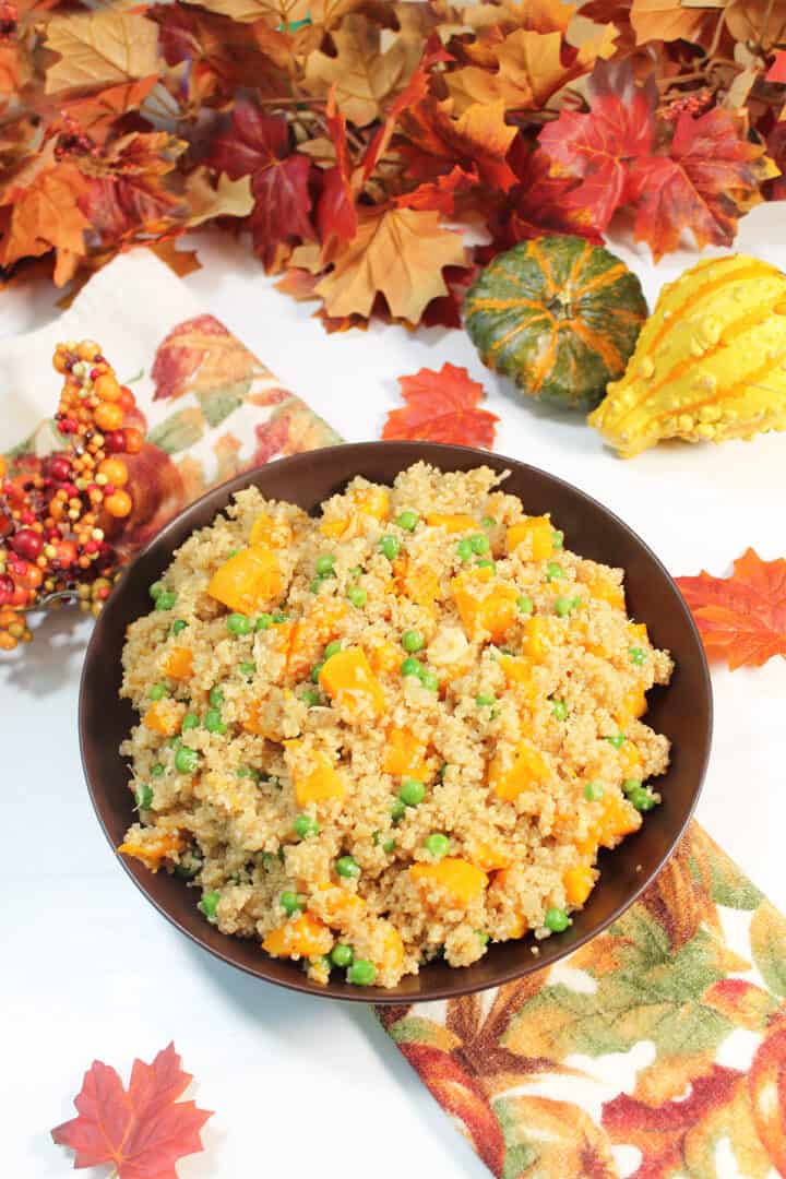 Overhead of butternut squash quinoa pilaf in brown bowl on white table.