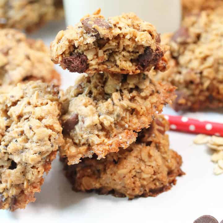 Stacked oatmeal chocolate chip cookies on white table.