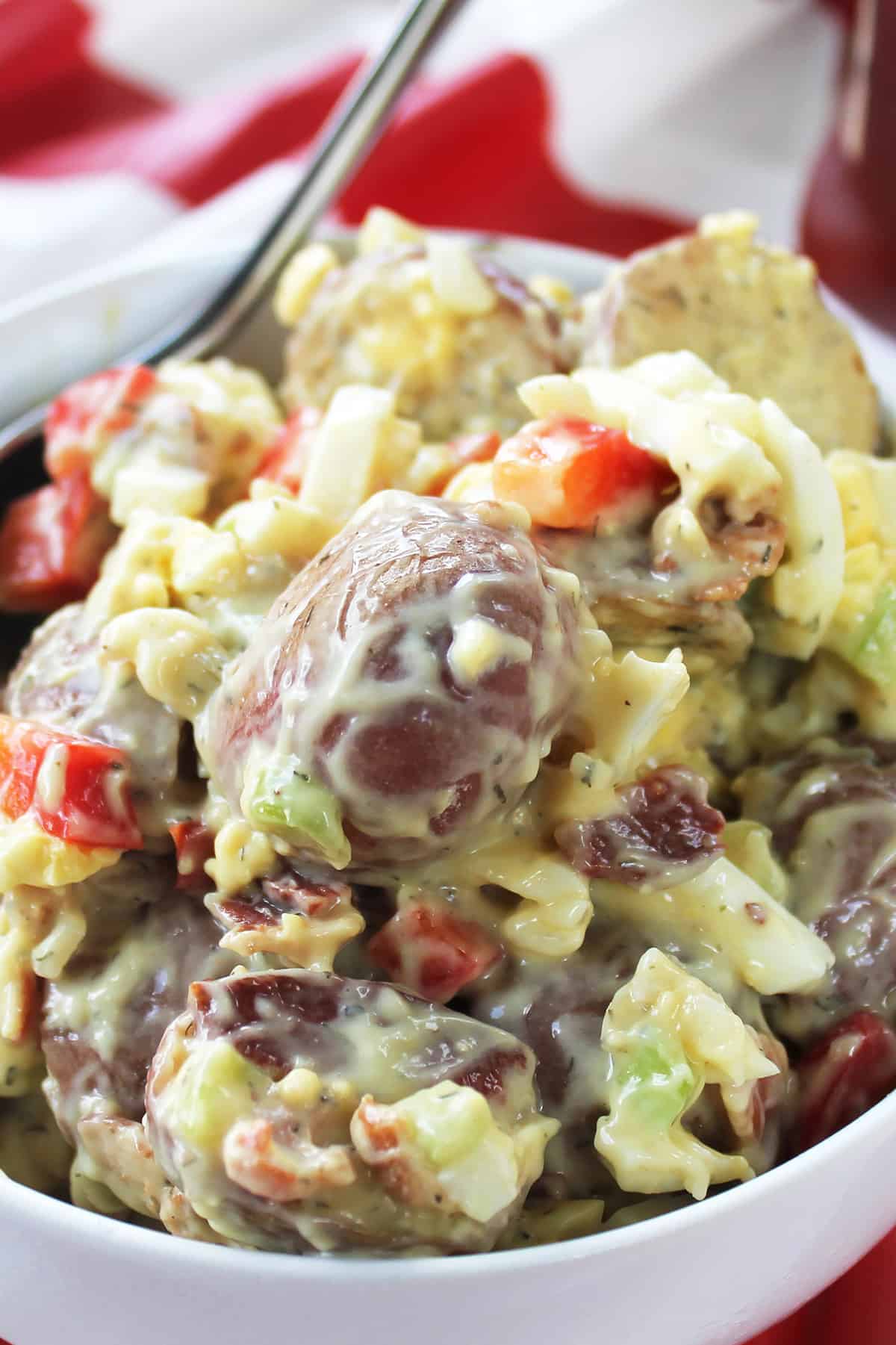 Bowl of Red Dill Potato Salad on red striped table.