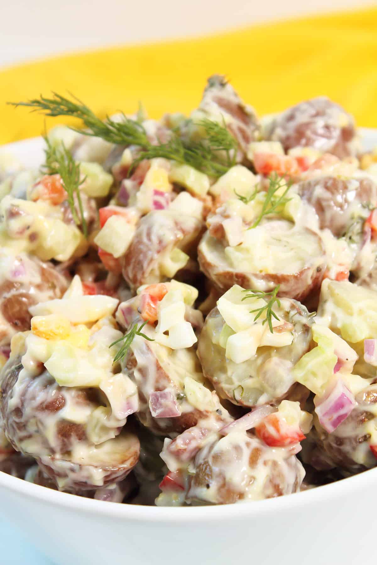 Closeup of red skin potato salad in white bowl.