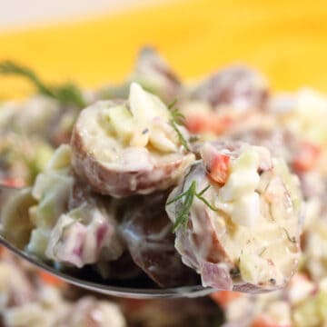 Spoonful of red dill potato salad with sour cream and bacon.