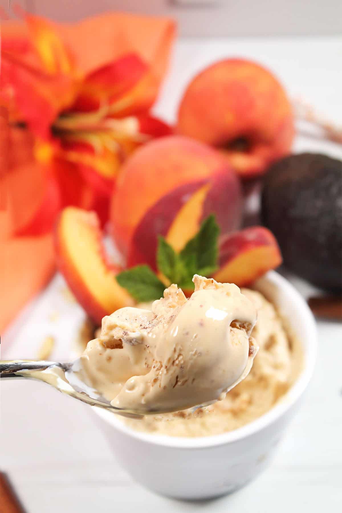Spoonful of peach ice cream over bowl.