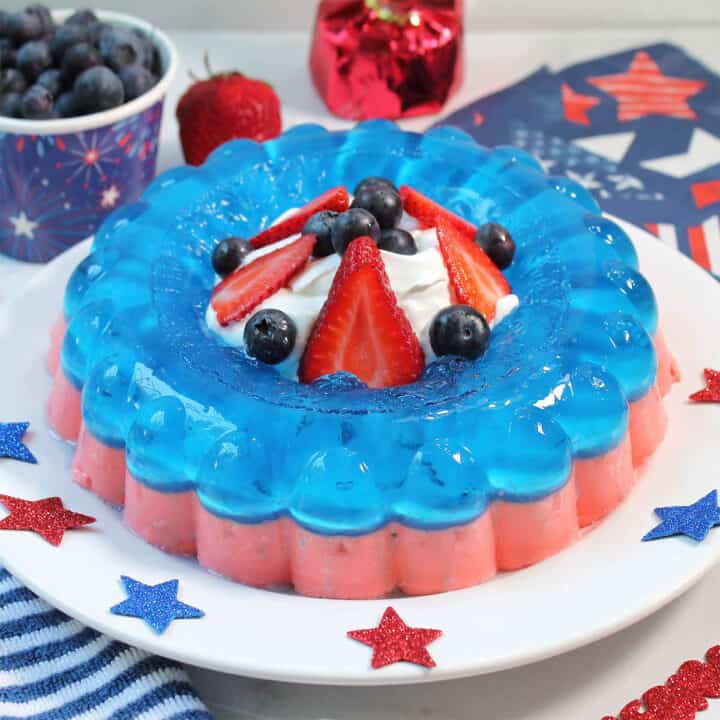Patriotic Jello Salad on white table with blueberries and confetti stars.