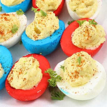 Closeup of patriotic deviled eggs with paprika and parsley garnish.