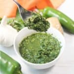 Lifting spoonful of sauce over bowl.