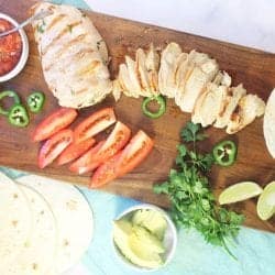 Overhead of grilled chicken and ingredients on wooden board.