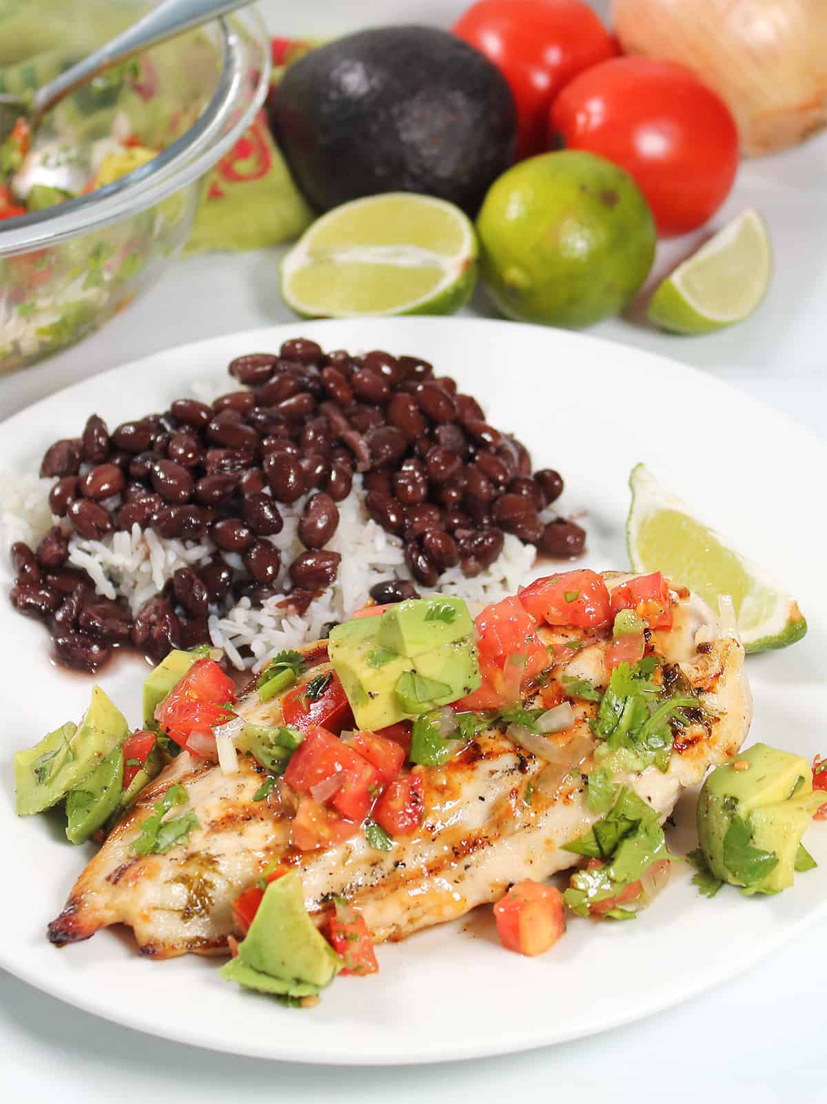Grilled chicken plated with avocado salsa on top.