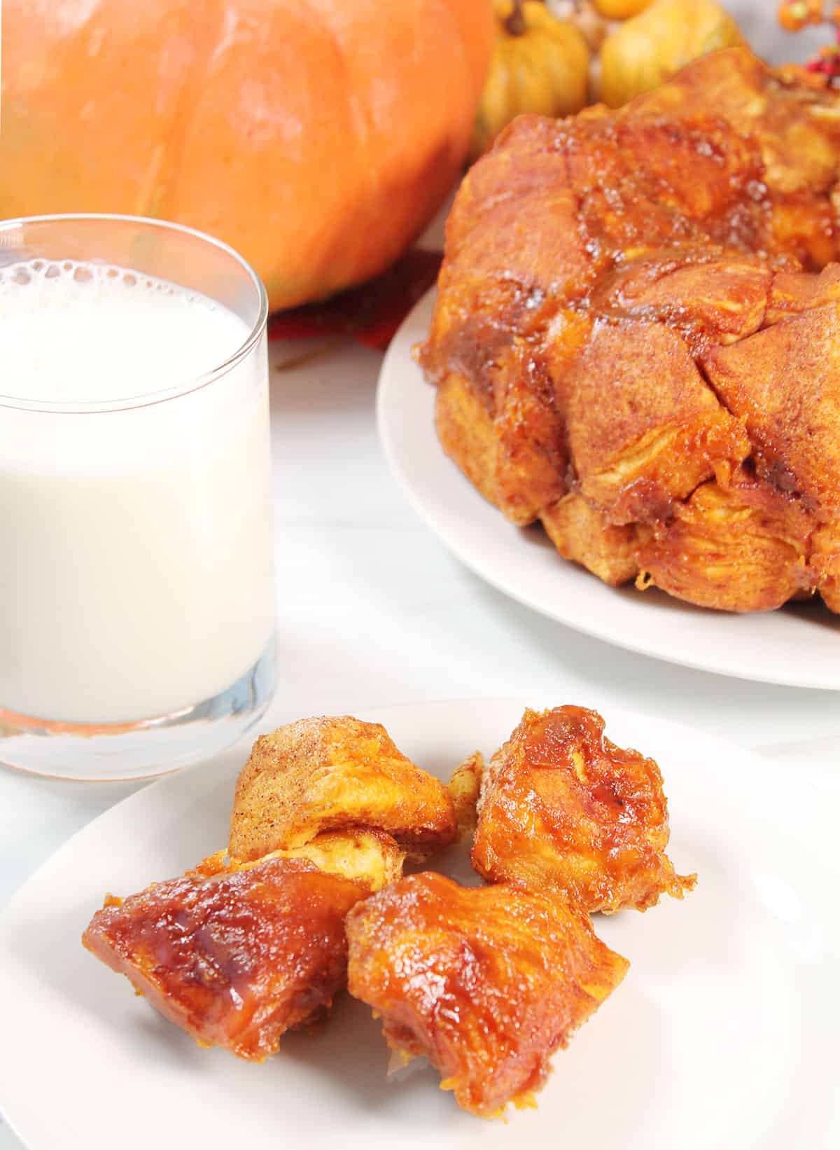Serving of pieces of monkey bread on plate in front of bread.