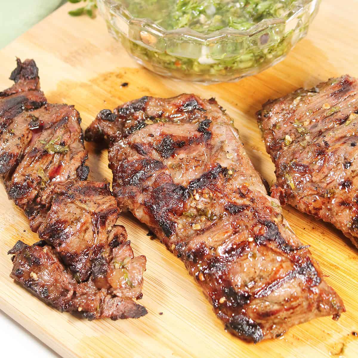 Grilled chimichurri steak on cutting board.