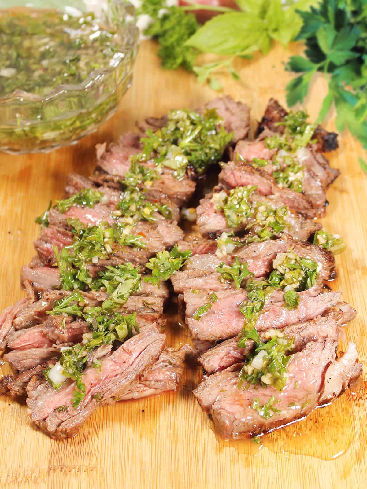 Sliced skirt steak with chimichurri sauce over the top.